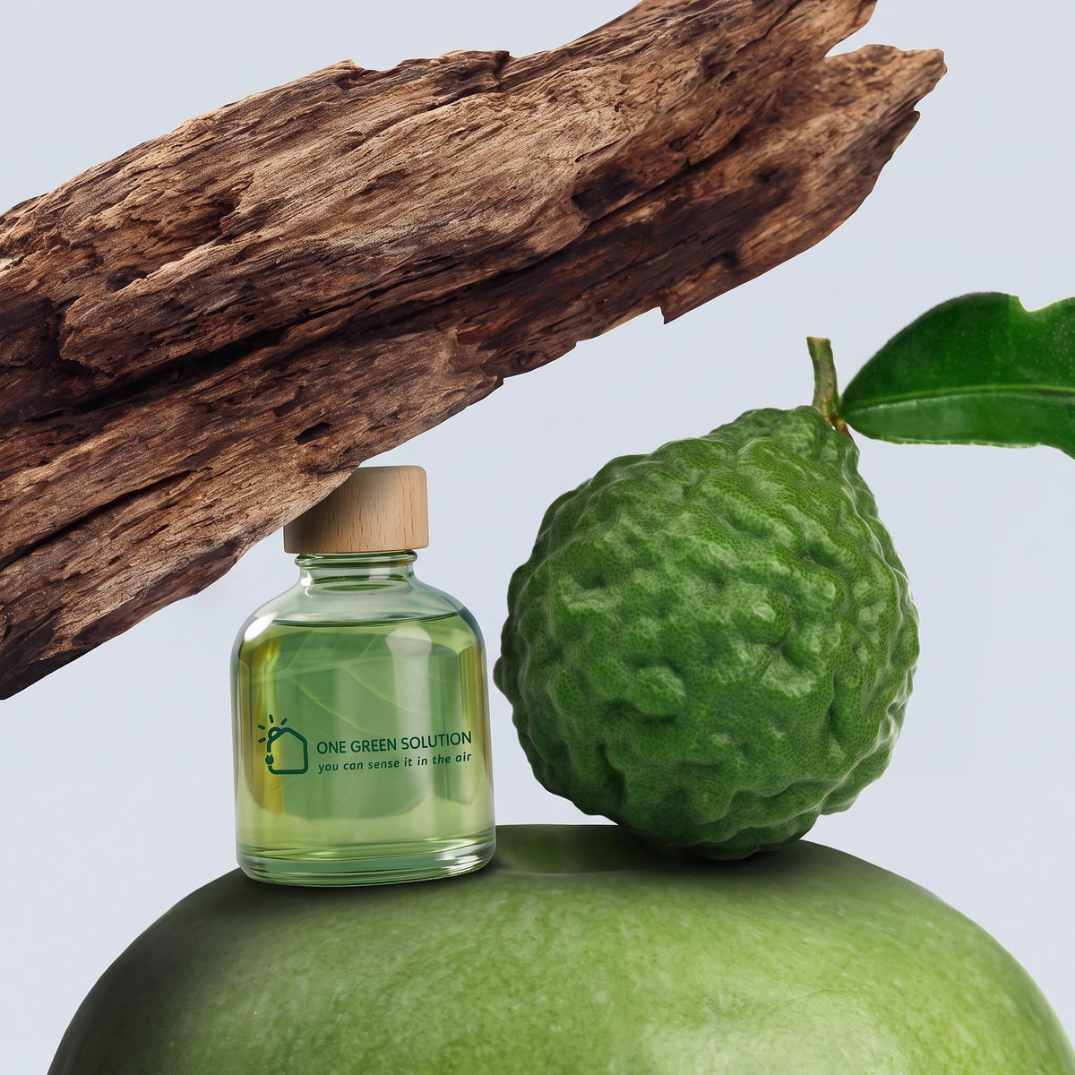 Citrus Wood Signature Scent oil bottle beside a fresh bergamot and a piece of weathered wood