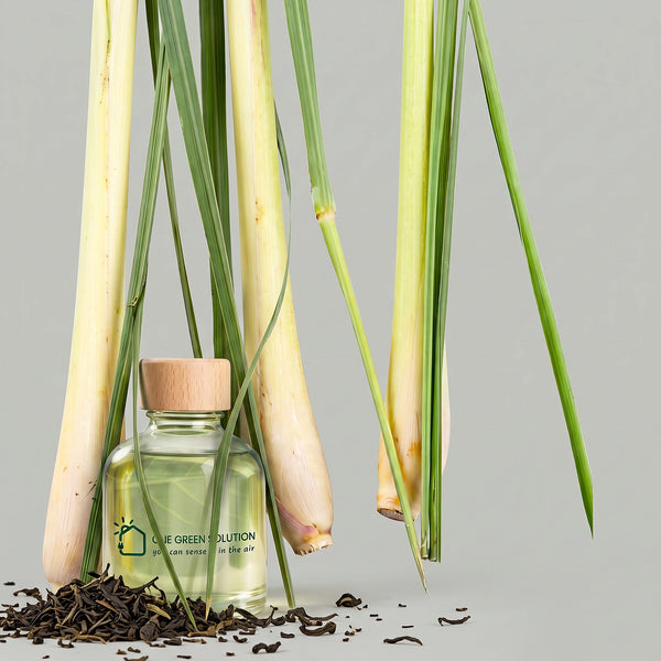 Green Tea Lemongrass Signature Scent oil bottle among lemongrass stalks and loose green tea leaves