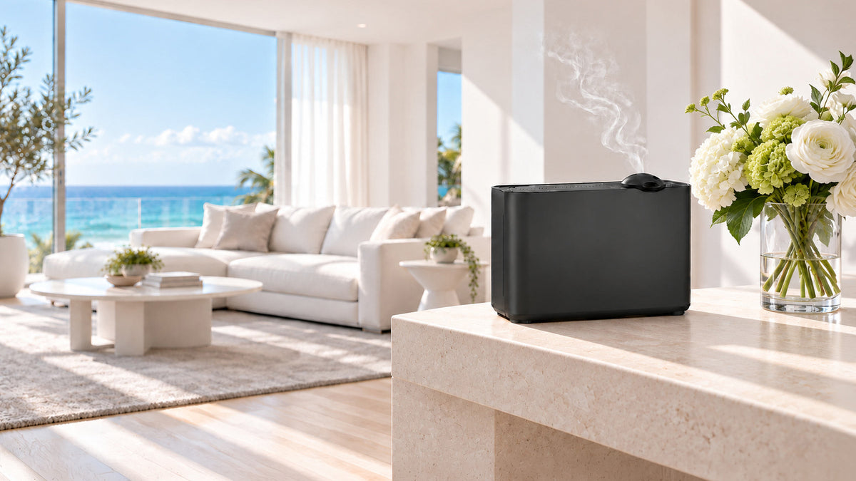Black scent diffuser releasing a light mist beside white flowers in a bright South Florida living room