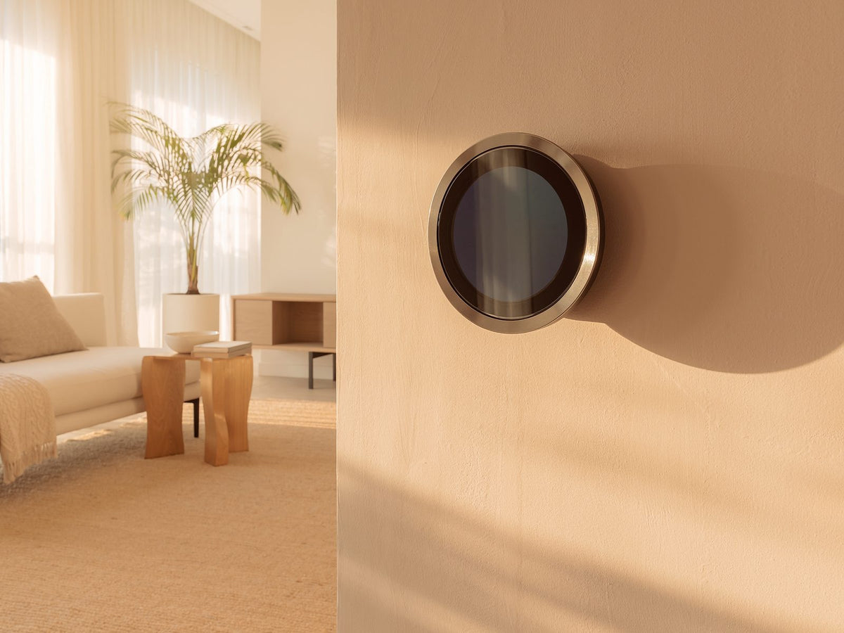 Nest smart thermostat with a brushed bronze ring on a warm beige wall