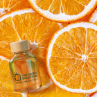 Sunny Citrus Signature Scent oil bottle on a bed of fresh orange slices